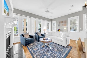 A spacious living room with a white sofa, blue armchairs, a coffee table, and a large window with blinds. - When you need a getaway, Beach Therapy is the cure! (Panama City Beach)