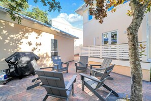 An outdoor patio with Adirondack chairs, a barbecue grill, and a brick floor. - When you need a getaway, Beach Therapy is the cure! (Panama City Beach)