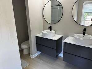 Un baño con dos lavamanos, un inodoro y un espejo.
