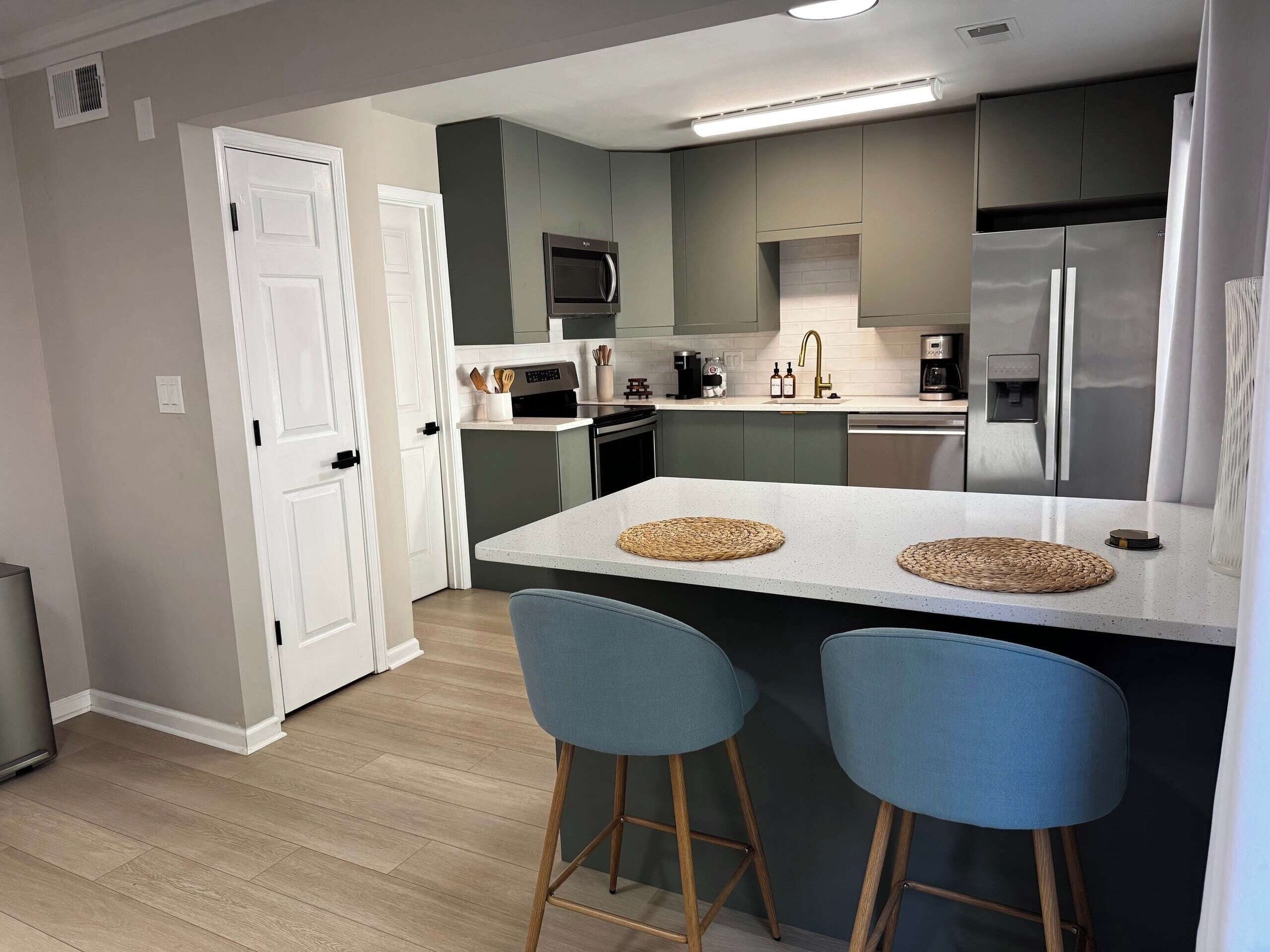 A modern kitchen with a central island, bar stools, and stainless steel appliances.