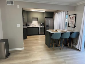 A modern kitchen with a central island, bar stools, and a dining table. - Cozy & family-friendly 3-bedroom townhome in Roswell/Alpharetta /Johns Creek (Roswell)
