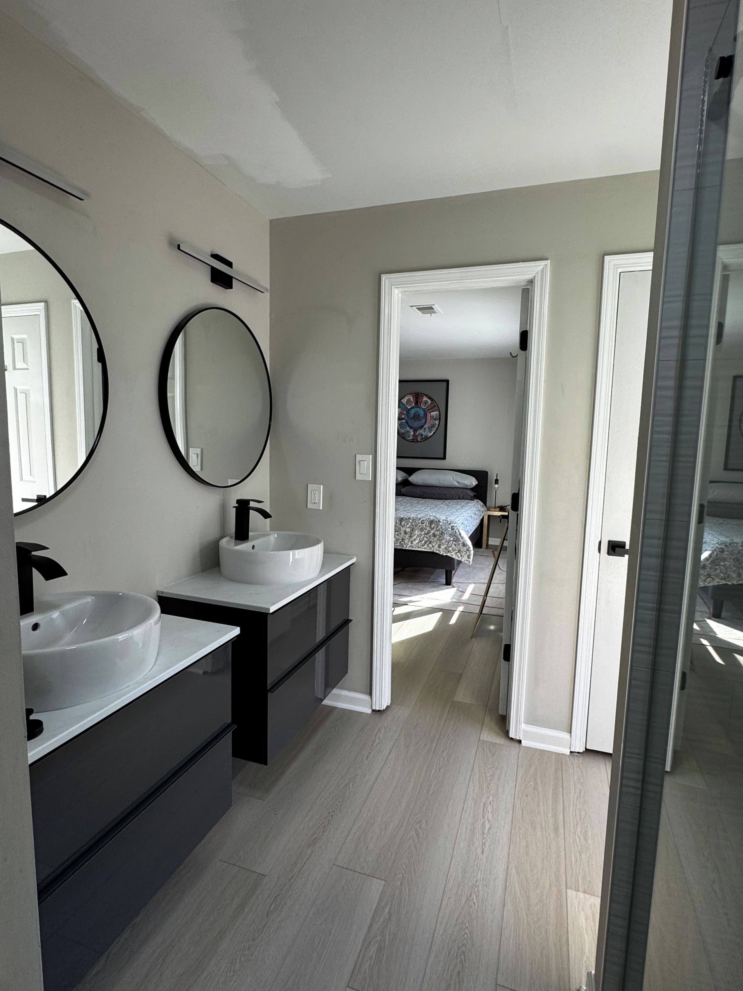 A modern bathroom with a double sink, a large mirror, and a walk-in shower.