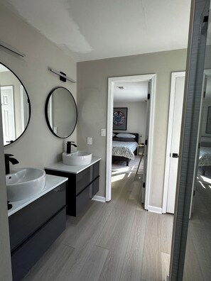 Un baño moderno con lavamanos doble, un espejo grande y una ducha a ras de suelo.
