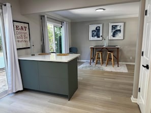 A modern kitchen with a central island, wooden stools, and a dining table. - Cozy & family-friendly 3-bedroom townhome in Roswell/Alpharetta /Johns Creek (Roswell)