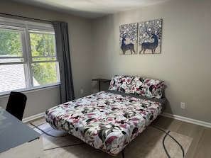 A bedroom with a bed, a desk, a chair, a window with curtains, and two wall-mounted paintings. - Cozy & family-friendly 3-bedroom townhome in Roswell/Alpharetta /Johns Creek (Roswell)