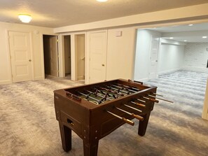 A room with a foosball table, carpeted flooring, and white doors. - Spacious 2-bedroom + office home in beautiful Idaho Falls-30 day minimum (Idaho Falls)