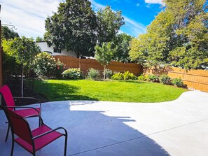 A backyard with a patio area, a wooden fence, and a lawn. - Spacious 2-bedroom + office home in beautiful Idaho Falls-30 day minimum (Idaho Falls)