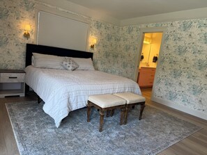 Ein Schlafzimmer mit einem Bett, Nachttischen, einer Bank und einem Beistelltisch.