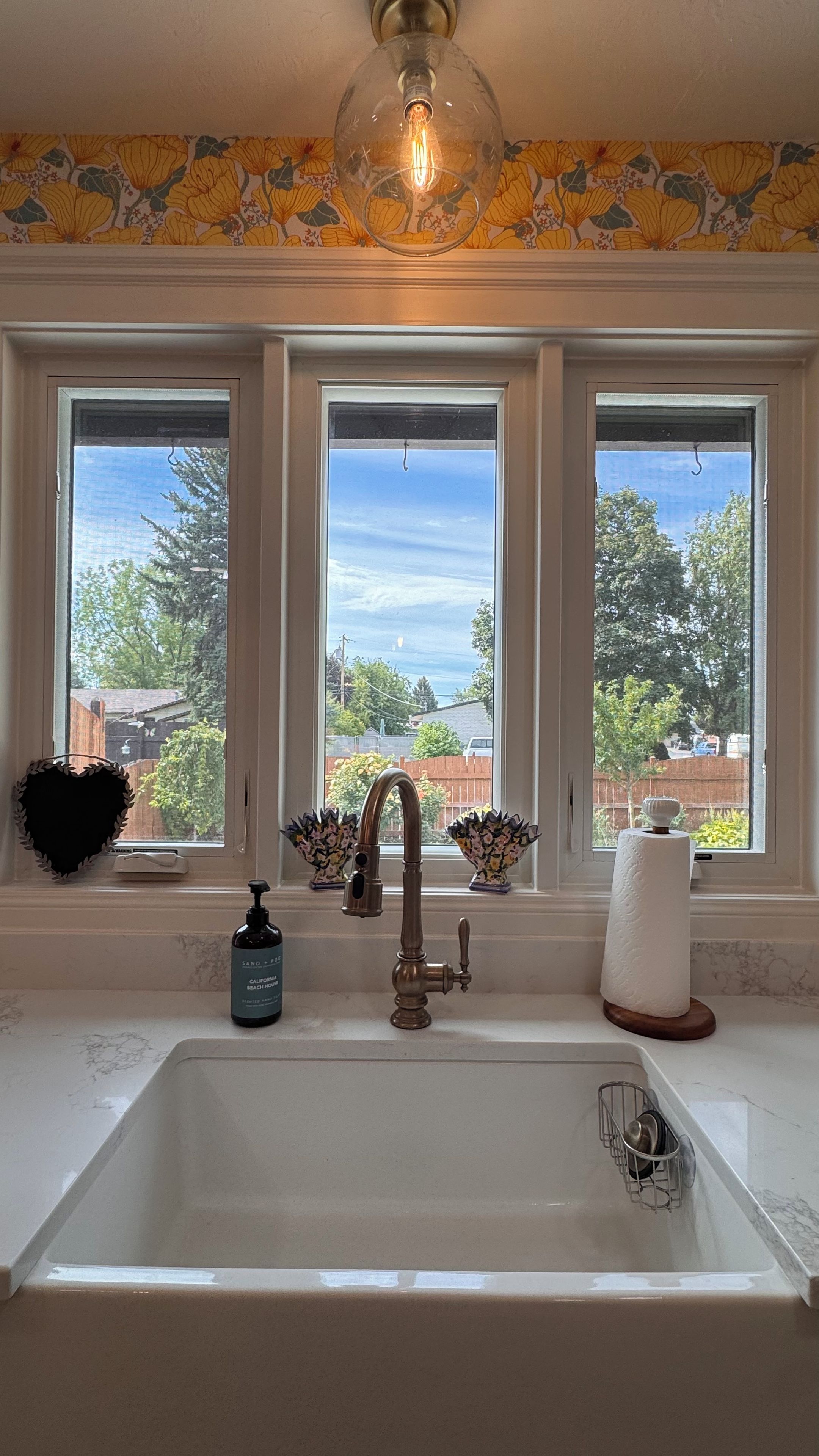 A kitchen with a white sink, a faucet, and a window above it.