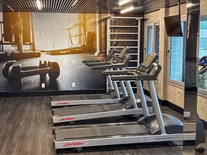 Ein Fitnessstudio mit Laufbändern, Gewichten und einer großen Spiegelwand.