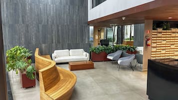 A modern lobby with a curved wooden bench, a white sofa, and a reception desk.