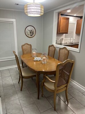A dining room with a wooden table, six chairs, and a chandelier. - Pixie’s Haven A Home Away From Home (Monroe)