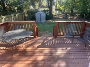 A wooden deck with metal chairs and a table, surrounded by a wooden fence and trees. - Pixie’s Haven A Home Away From Home (Monroe)