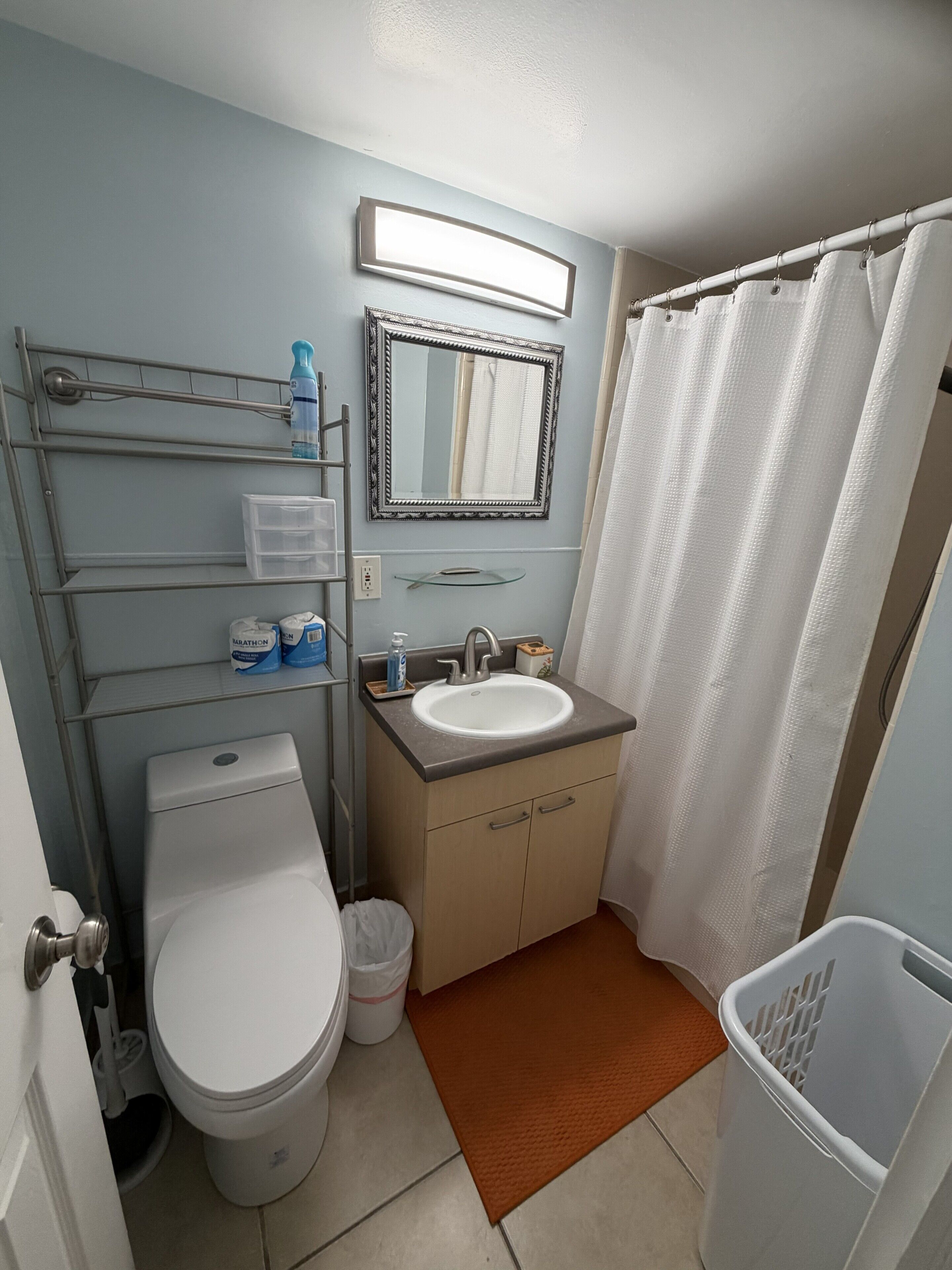 Un baño con inodoro, lavamanos, espejo y cortina de ducha.