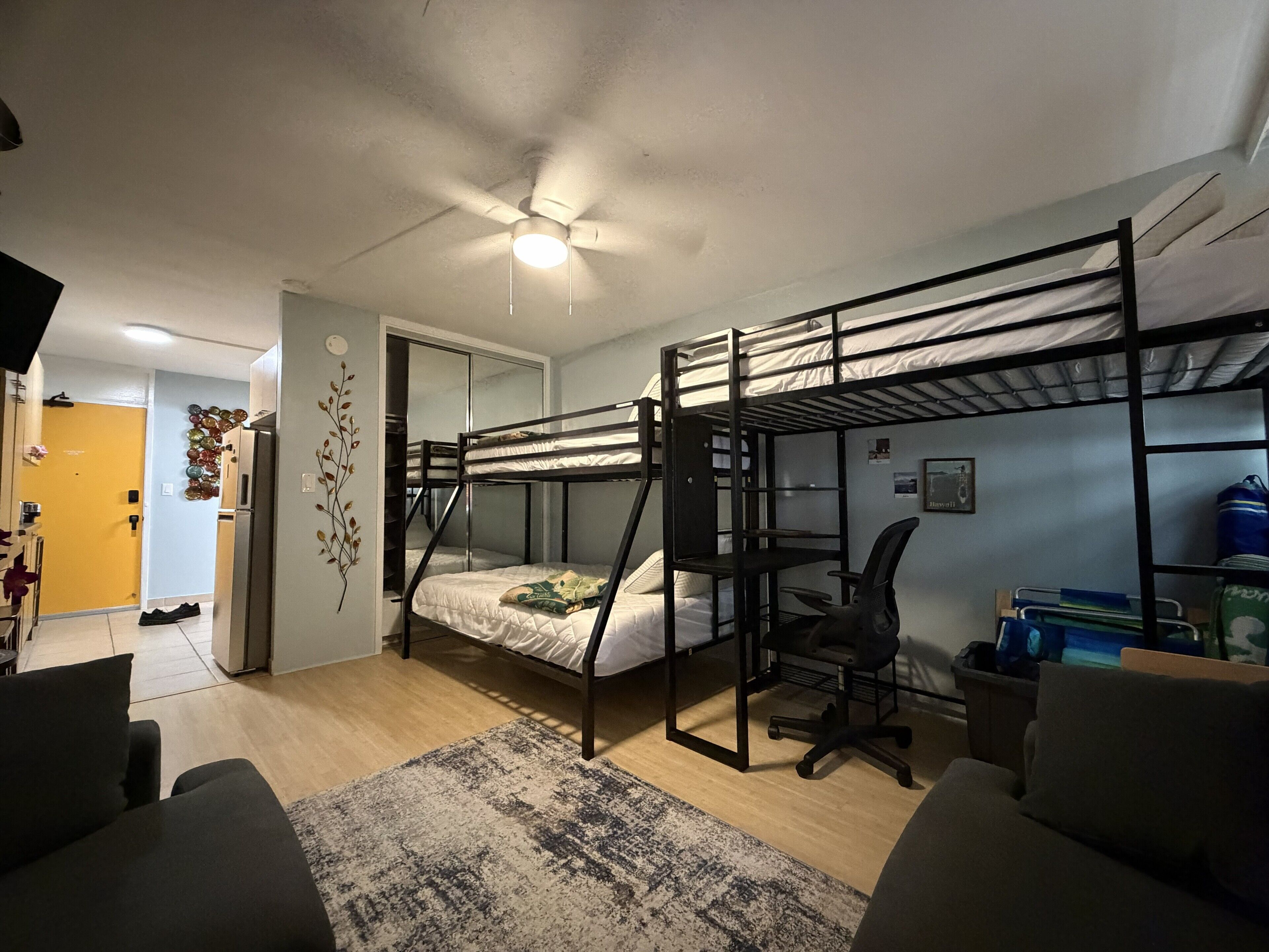 A bunk bed room with a desk, chair, and a ceiling fan.