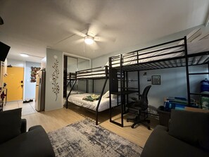 A bunk bed room with a desk, chair, and a ceiling fan. - Surfer's Sanctuary at Waikiki Beach (Honolulu)