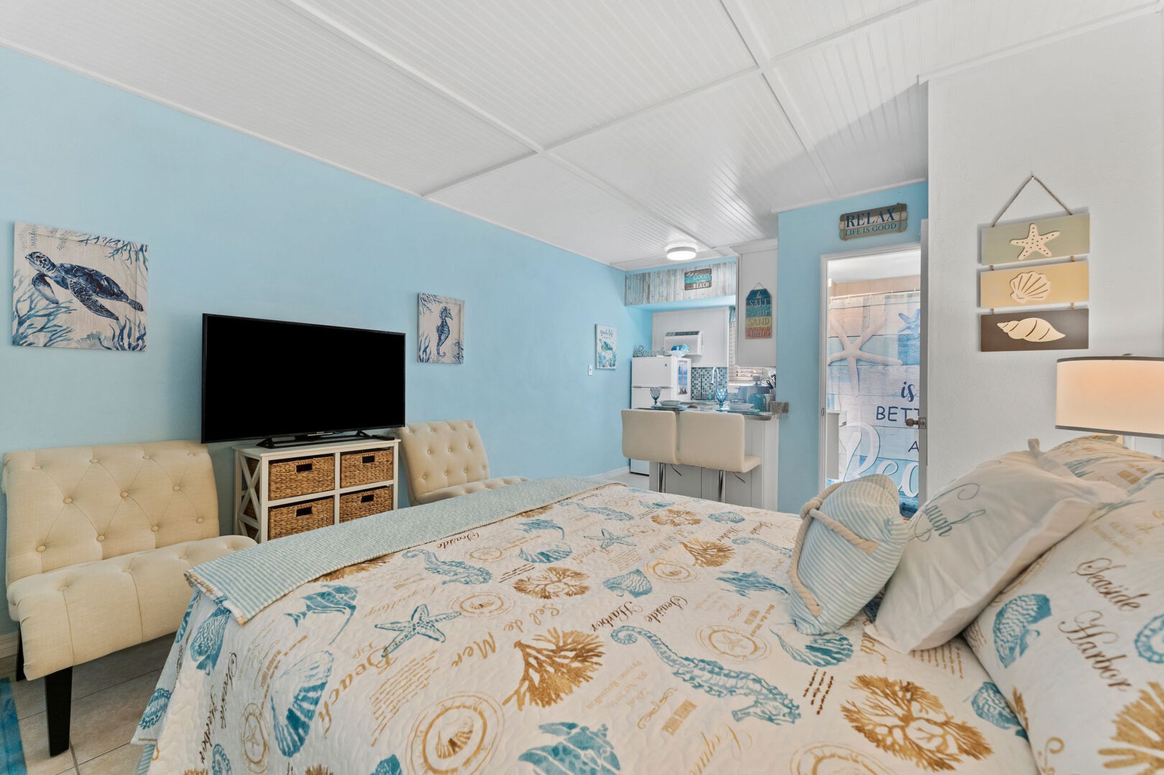A bedroom with a bed, a television, a dresser, and a dining area.