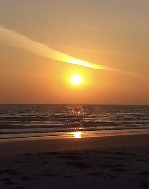 Un atardecer sobre una playa con olas.