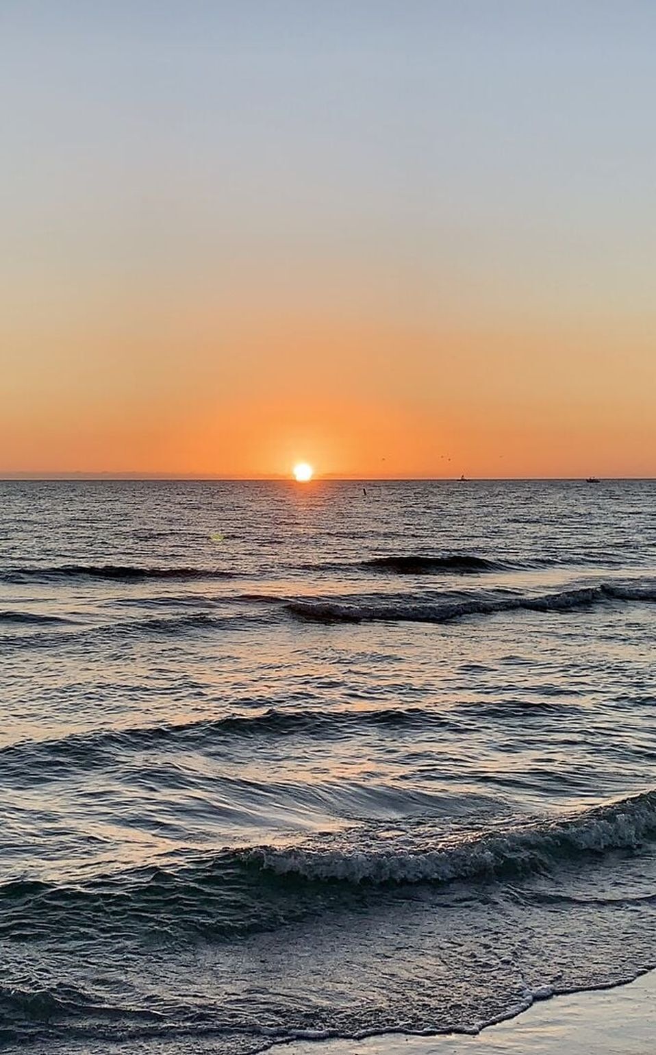 A sunset over the ocean with waves.