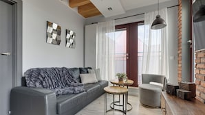 Ein modernes Wohnzimmer mit einem grauen Sofa, einem runden Holztisch, einem grauen Sessel und einer Wand mit Backsteinverkleidung.