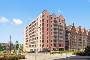 A multi-story residential building with balconies and a parking area in front. - Waterlane Island - Pool Sauna and Gym (Gdańsk)