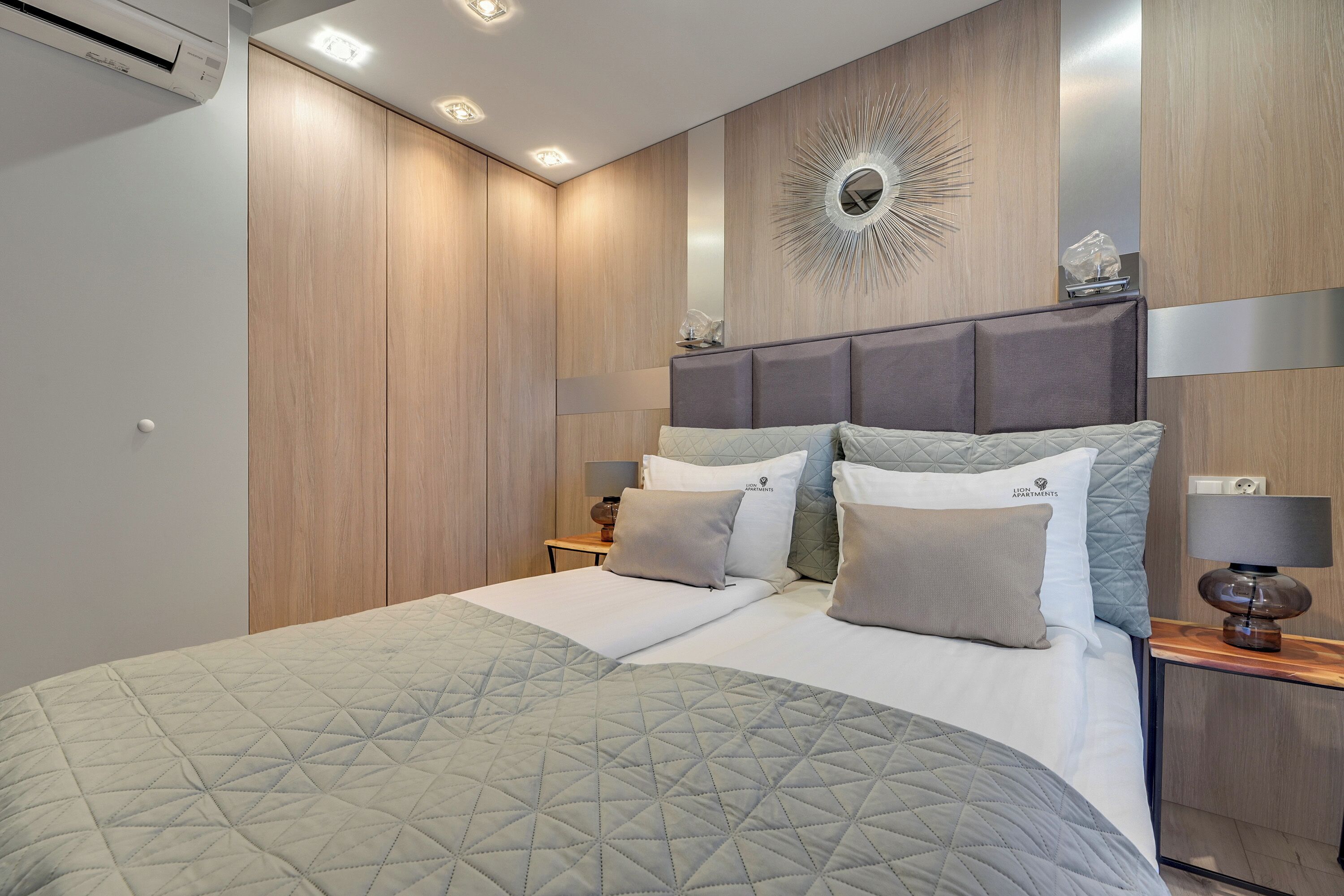 Un dormitorio moderno con una cama grande, cabecera con iluminación integrada, un adorno en la pared y una mesita de noche con lámpara.
