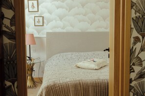 Ein Schlafzimmer mit einem Bett, einem Nachttisch, einer Lampe und einer Wand mit strukturierter Oberfläche.