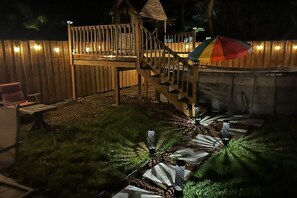 A backyard with a wooden deck, a hot tub, and a colorful umbrella. - Relaxing Coastal Getaway – Near Beach & Shops (Clearwater)