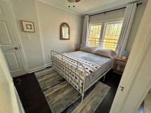 A bedroom with a bed, a window, a door, and a small bedside table. - Relaxing Coastal Getaway – Near Beach & Shops (Clearwater)