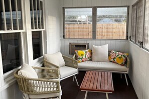 A sunlit room with a white sofa, two wicker chairs, and a wooden table. - Relaxing Coastal Getaway – Near Beach & Shops (Clearwater)