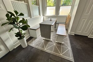 A room with a bench, a small table, and a potted plant. - Relaxing Coastal Getaway – Near Beach & Shops (Clearwater)