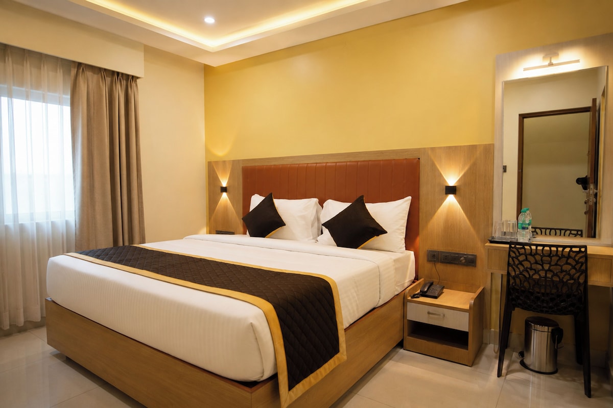 A hotel room with a large bed, bedside tables, a mirror, and a trash bin.