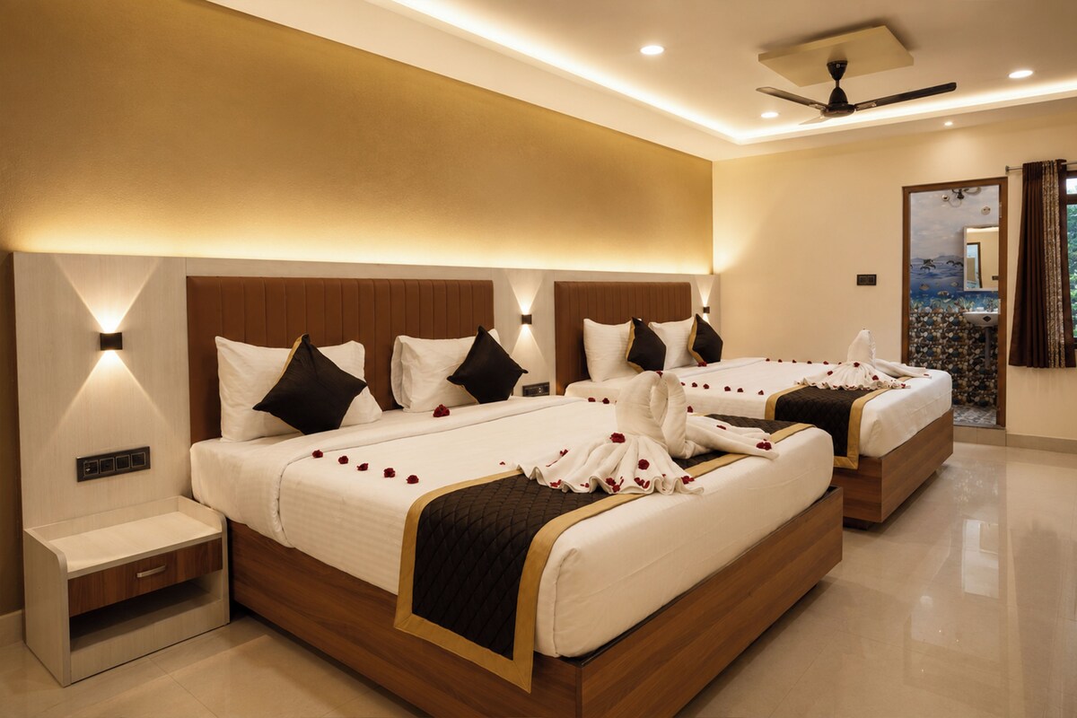 A hotel room with two beds, a nightstand, a ceiling fan, and a bathroom with a decorative mirror.