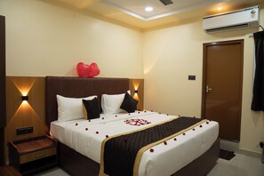 Een hotelkamer met een bed, nachtkastjes, een kledingkast en een airconditioning.
