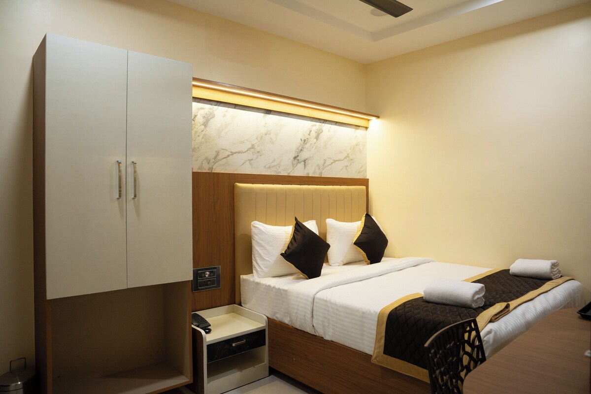 A hotel room with a bed, bedside table, and a wardrobe.