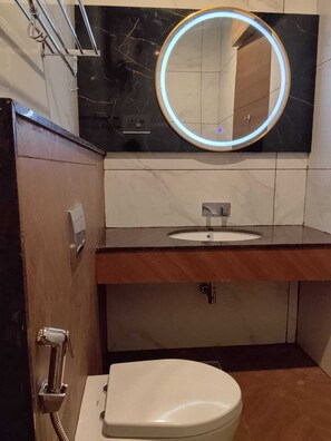 Un baño con inodoro, lavamanos y espejo con iluminación perimetral.