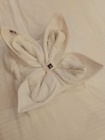 Una toalla blanca doblada con cuidado, con una etiqueta pequeña colocada sobre una superficie blanca lisa.