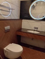 Un baño moderno con inodoro, lavamanos y espejo con luz circular.