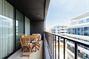 Un balcon avec une table et des chaises, donnant sur un paysage urbain.
