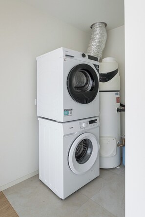 A stacked washer and dryer unit with a vent pipe above it. - Modern family apartment in Canidelo, Porto (Canidelo)