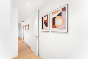 A hallway with a white door, wooden flooring, and two framed abstract artworks on the wall. - Modern family apartment in Canidelo, Porto (Canidelo)