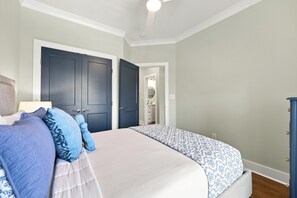A bedroom with a bed, pillows, a dresser, and a door leading to a bathroom. - Emerality | Steps to Beach, Private Elevator (Emerald Isle)