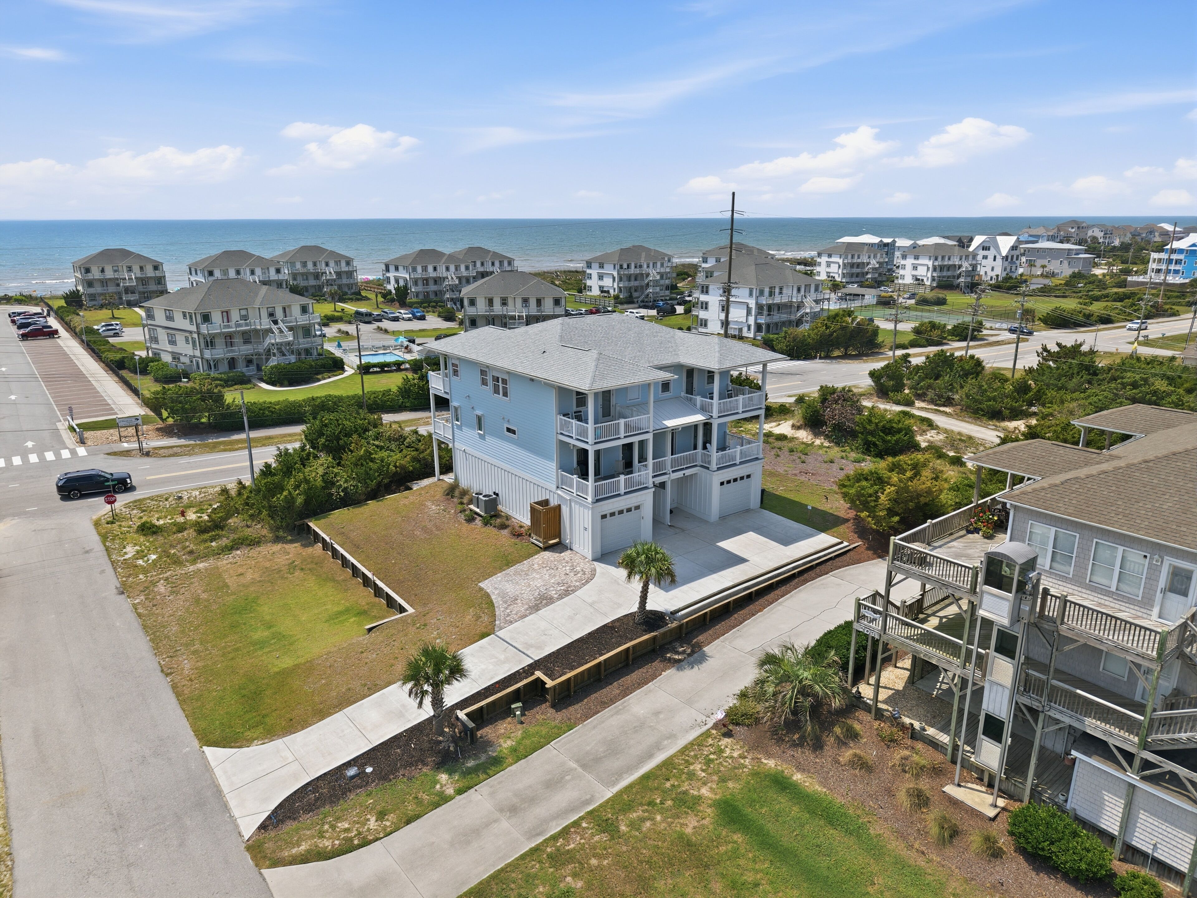 A coastal residential area with multiple two-story houses, a parking lot, and a clear view of the ocean.