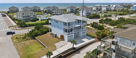 A coastal residential area with multiple two-story houses, a parking lot, and a clear view of the ocean.
