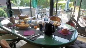 A glass-top dining table with various breakfast items, including bread, beverages, and a water bottle.