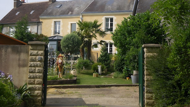 A residential building with a sloped roof, a satellite dish, and a gated entrance.