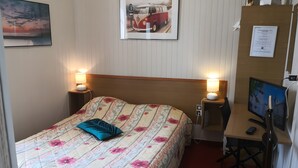 A hotel room with a bed, bedside lamps, a desk with a computer, and a TV.