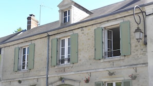 A building with multiple windows, a green door, and a small balcony with a railing.