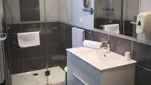A modern bathroom with a glass-enclosed shower, a white sink, and a large mirror.