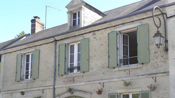 A building with multiple windows, a green door, and a small balcony with a railing.